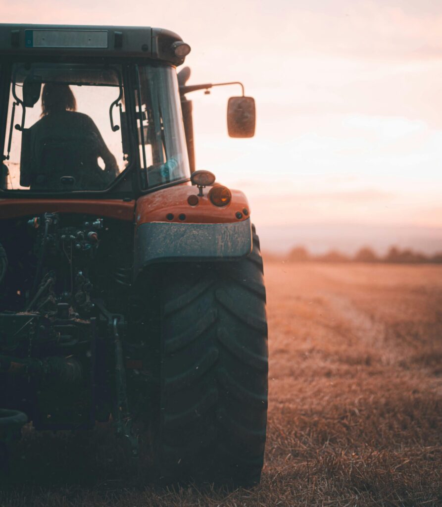A tractor sits in an open field at sunset, showcasing agriculture's beauty.